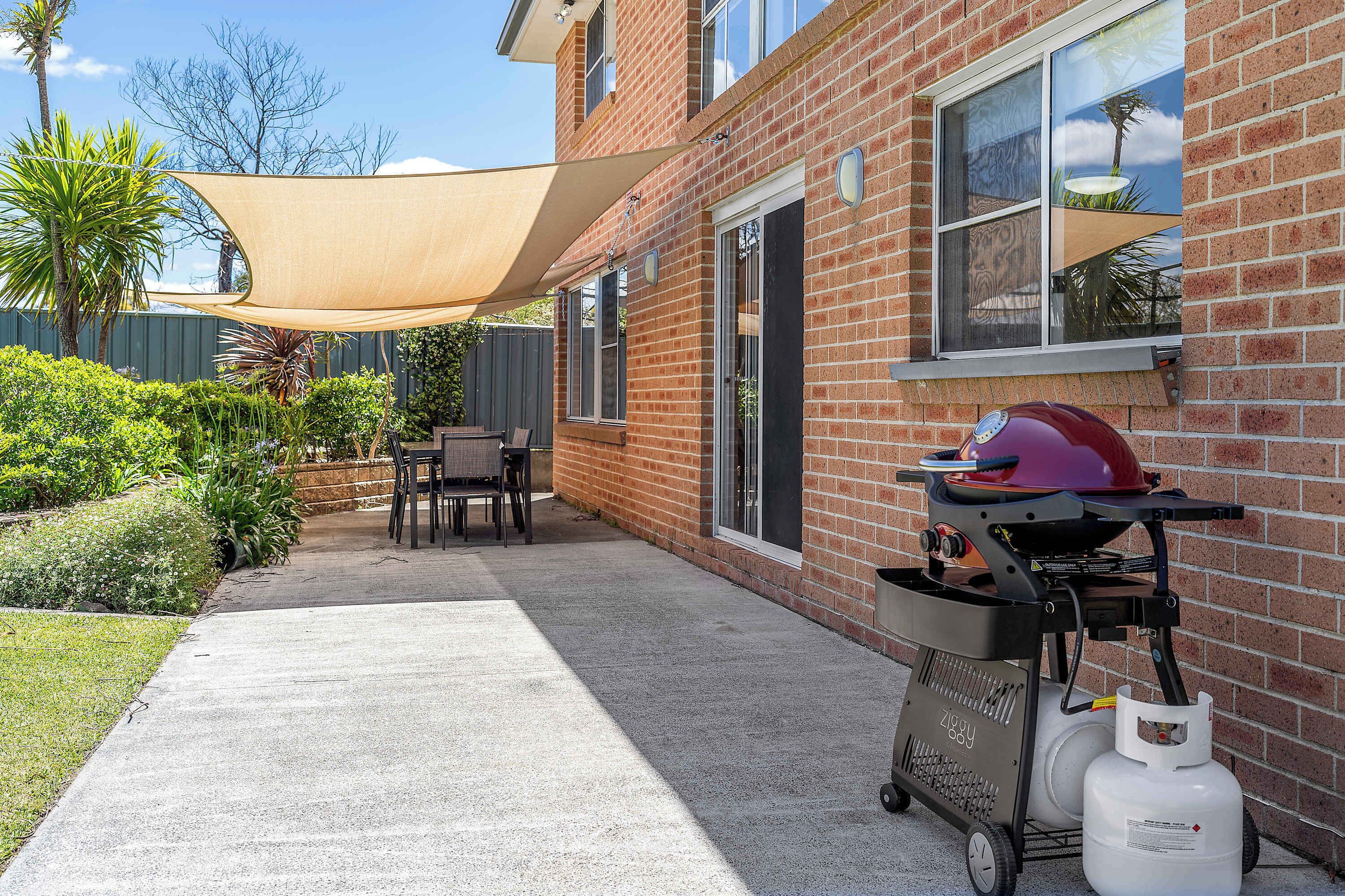 Un pati amb una zona de barbacoa, una taula i cadires.
