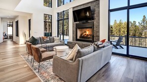 A modern living room with a fireplace, large windows, and a cozy seating area. - Pet Friendly | Minutes to Lift | Hot Tub | Blue Mountain Escape (Angel Fire)