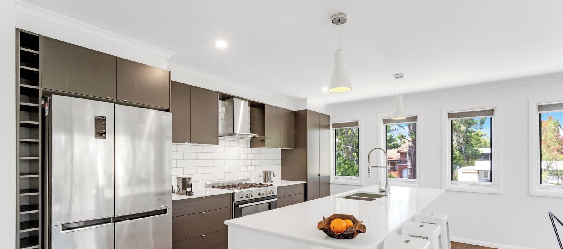 A modern kitchen with stainless steel appliances, a central island, and a view of the outdoors.