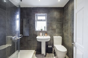Enjoy a clean and minimalistic bathroom with a pedestal sink, toilet, and glass-enclosed shower.