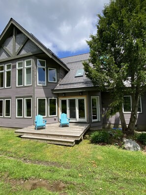 A two-story house with a deck and two blue Adirondack chairs. - Ski in Ski out - fantastic location on Raccoon Run (Jay)