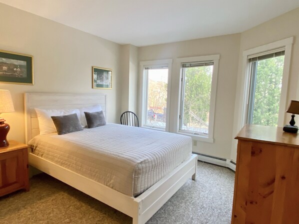 A bedroom with a bed, two windows, a chair, a nightstand, and a dresser. - Ski in Ski out - fantastic location on Raccoon Run (Jay)