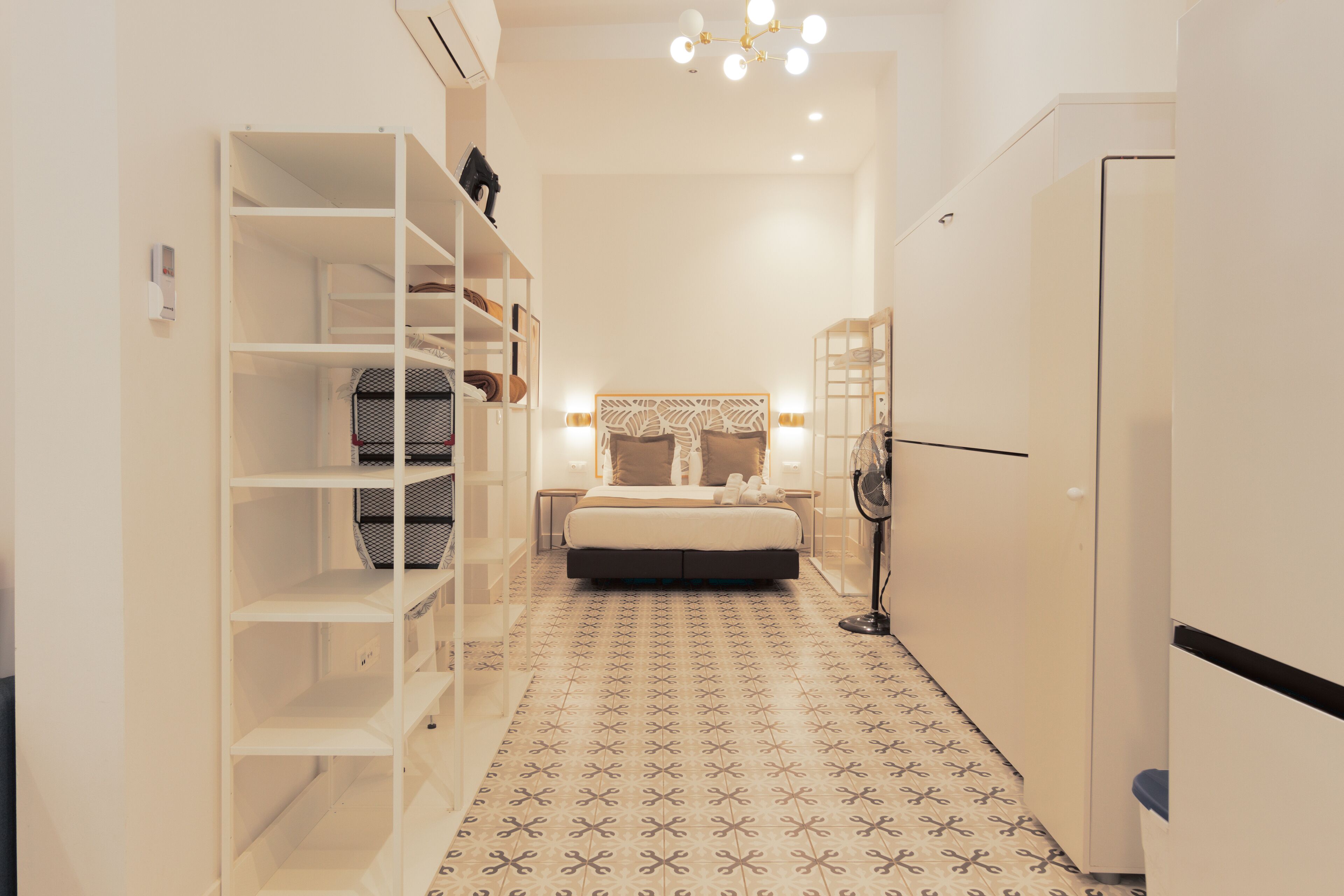 Un dormitorio con cama, armario, mesita de noche y ventilador de pared.