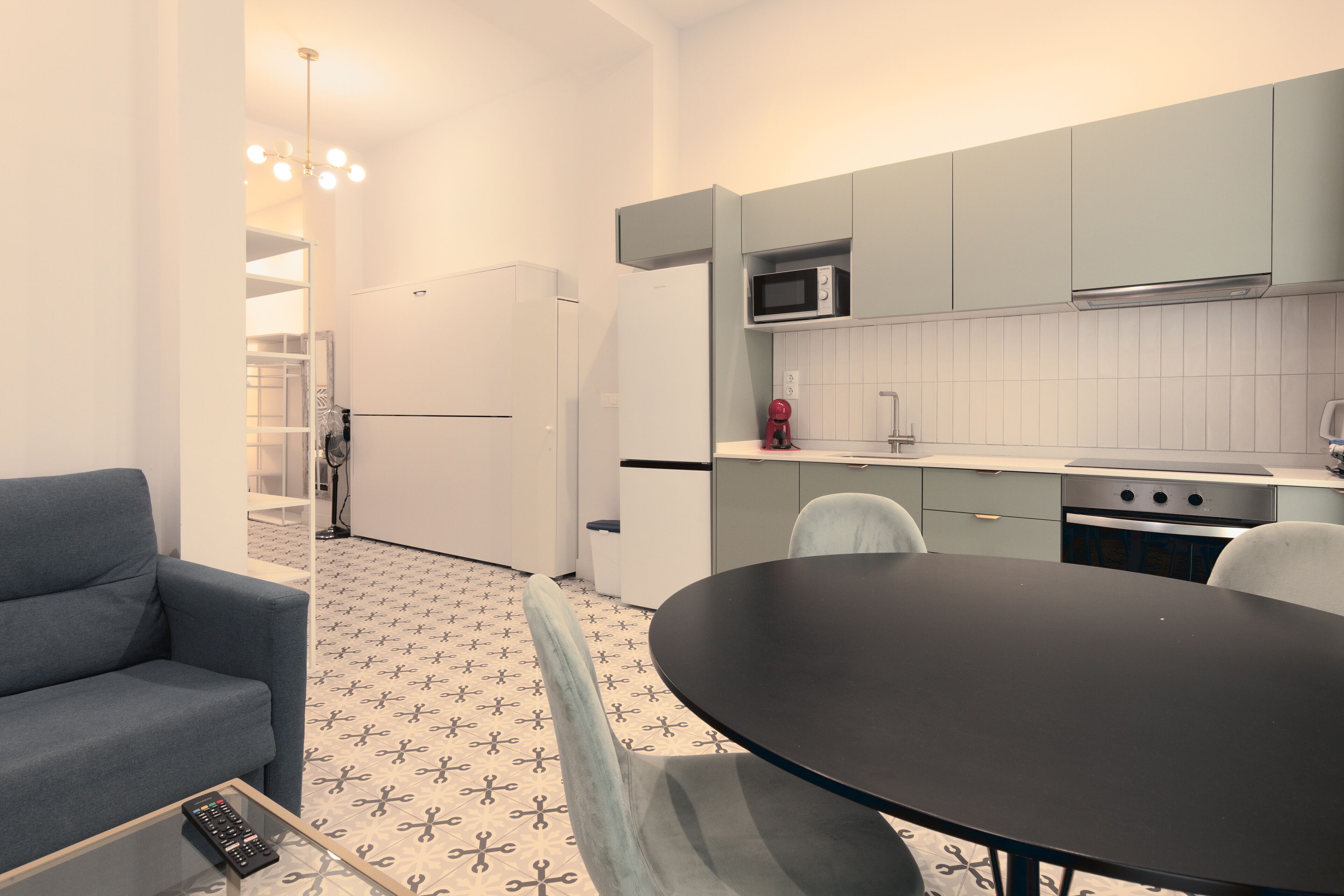 A compact kitchen with a dining area, a sofa, and a TV.