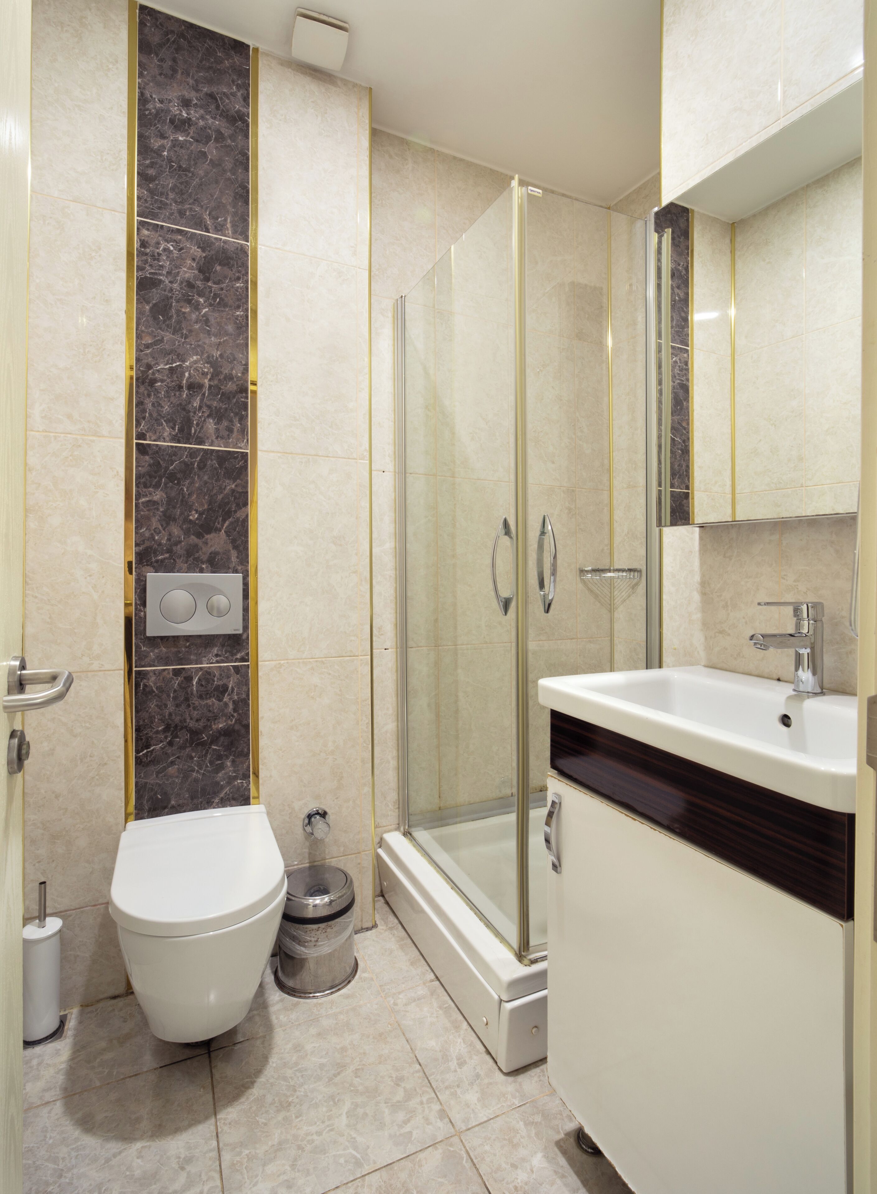 A modern bathroom with a toilet, a shower enclosure, and a sink with a mirror.