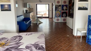 Sala de estar con sofá azul, una mesa de comedor y una cocina al fondo.