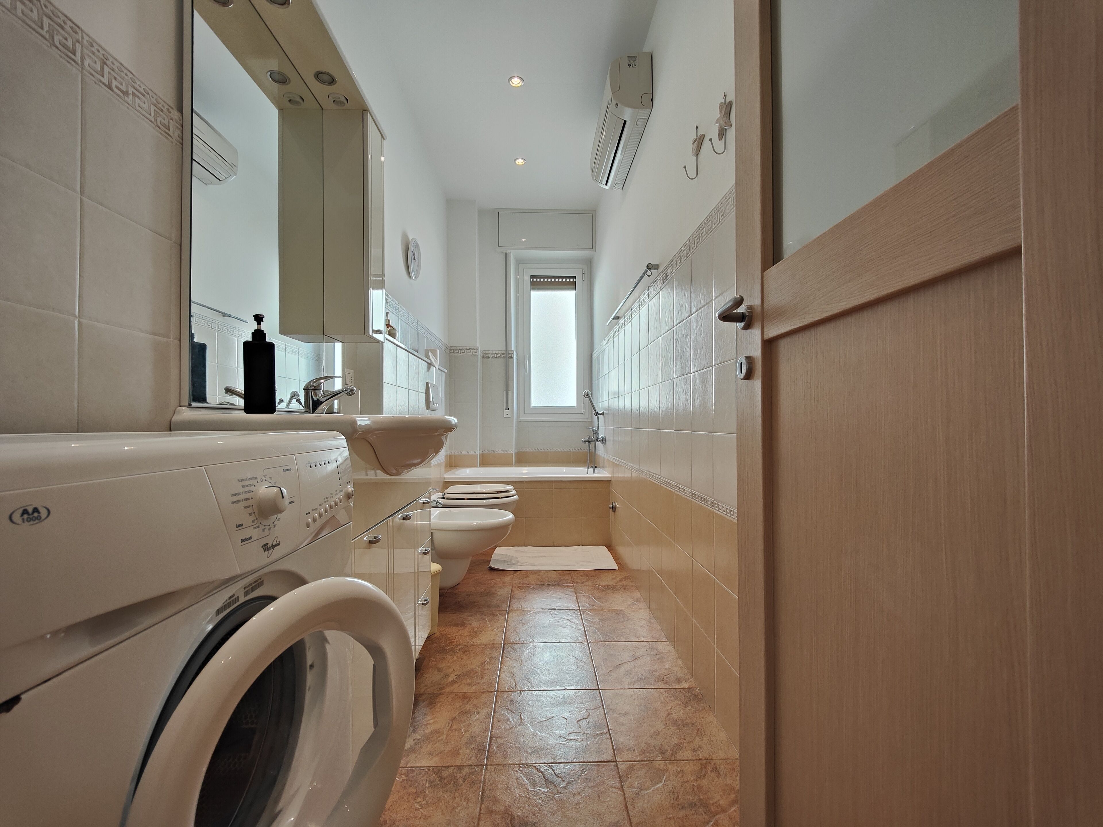 Ein modernes Badezimmer mit Waschmaschine, Waschbecken, Toilette und Dusche.