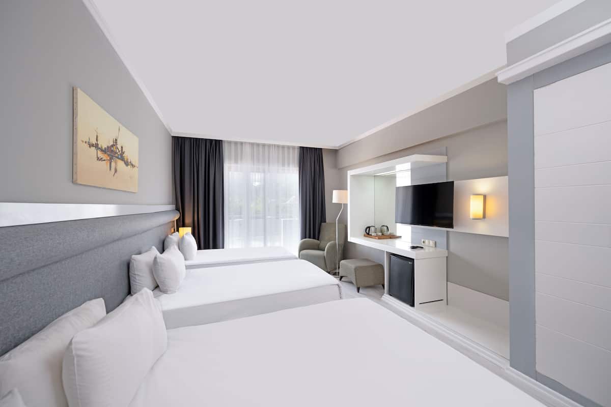 Ett modernt hotellrum med en stor säng, ett skrivbord, en stol, en TV och en tavla på väggen.