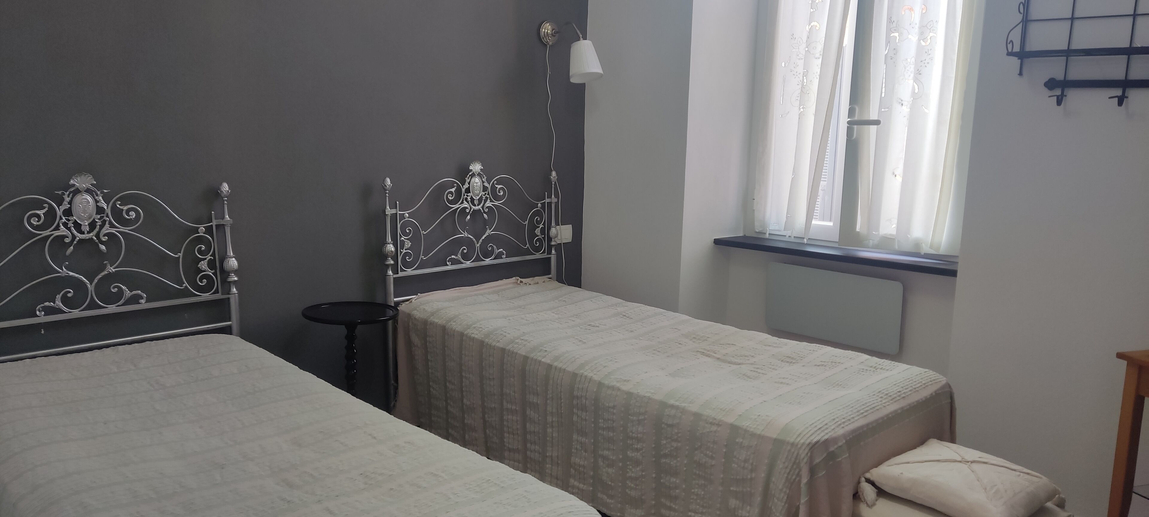 A bedroom with two beds, a bedside table, a lamp, and a window with curtains.