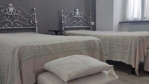 Een slaapkamer met twee bedden, elk voorzien van een decoratief hoofdeinde en een nachtkastje.