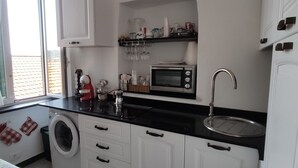 Een kleine keuken met een wasmachine, een magnetron en een spoelbak.