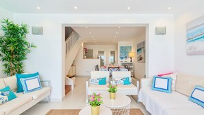 Ein modernes Wohnzimmer mit einer Sofagarnitur, einem Couchtisch und einer großen Topfpflanze.