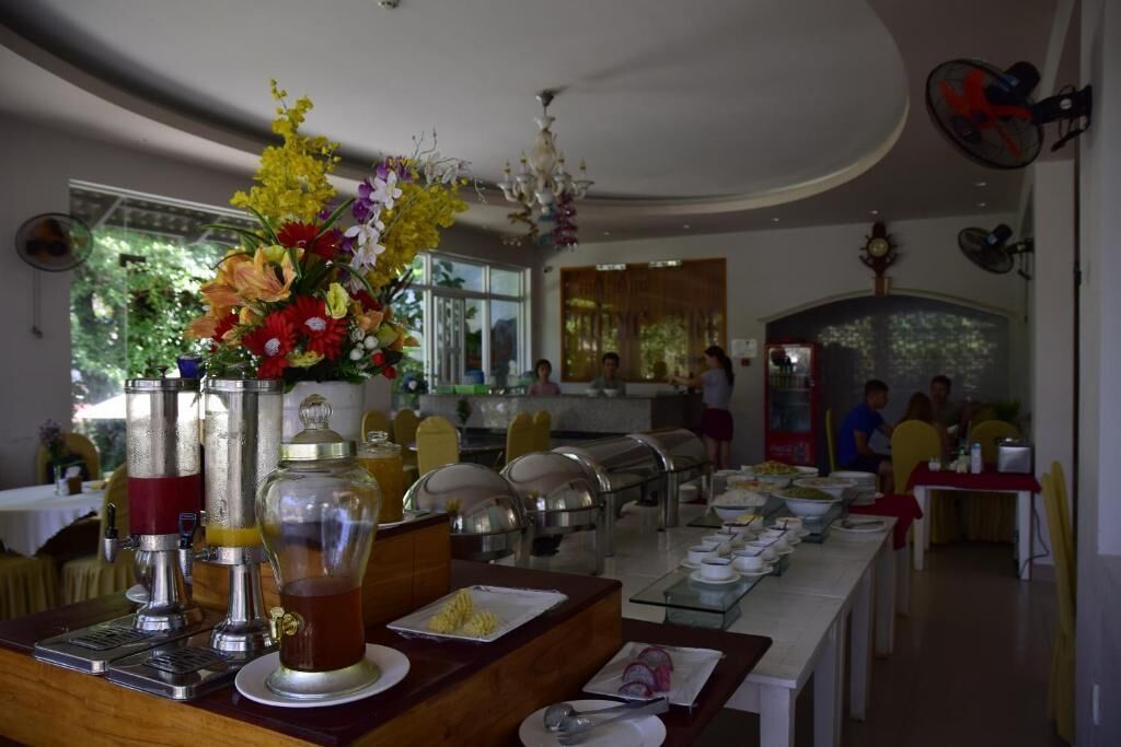 Montaje tipo bufé con distintas estaciones de comida, un centro de mesa floral y un área de comedor con mesas y sillas.