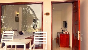 A room with a bed, a table, and chairs, a wooden cabinet, and a door with the number 301. - Hong Bin Bungalow Resort (Phu Quoc)