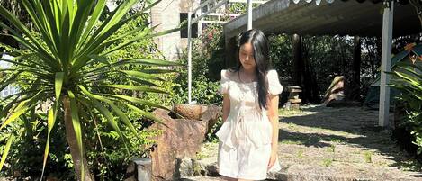 A person walking on stone steps surrounded by greenery and a building with a white structure.