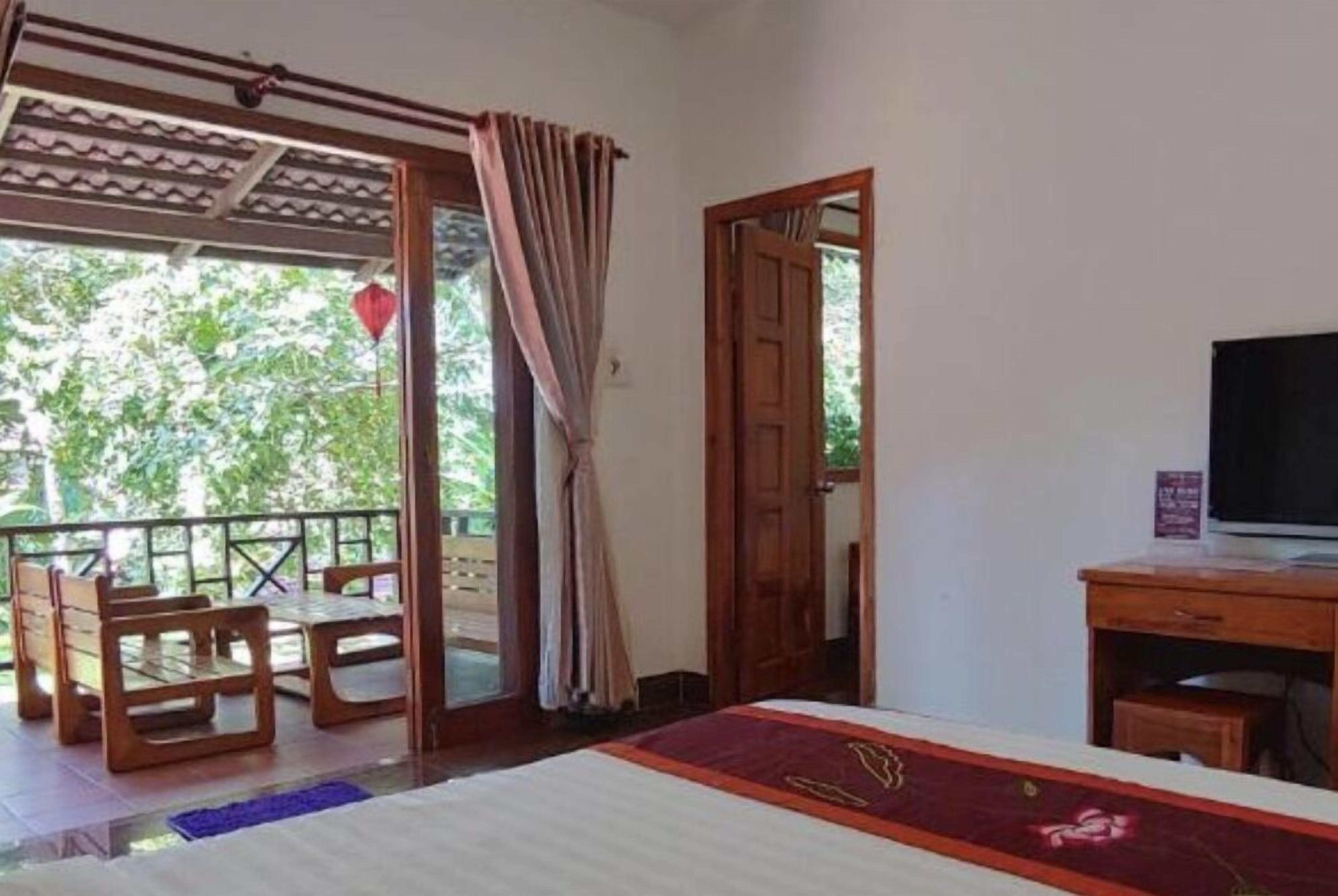 A room with a bed, a desk, and a balcony with wooden furniture.