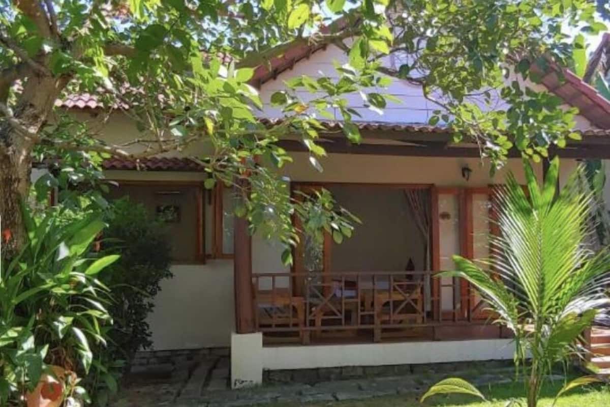 A house with a porch, surrounded by greenery and a small garden.