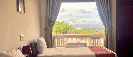 A hotel room with two beds, a view of the outdoors, and a balcony with a table and chairs.