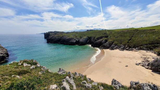 A coastal landscape with a sandy beach, clear turquoise waters, and rocky cliffs. - Apartamento A (Picones)