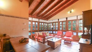 A cozy room with a wooden ceiling, large windows, a sofa, chairs, and a table. - Apartamento B (Picones)