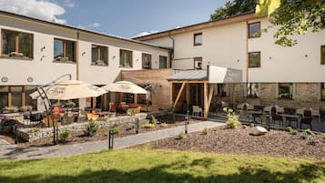 A hotel courtyard with outdoor seating, a stone pathway, and a sign for 'Royal Crown Cola'.