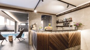 A modern bar area with a wooden counter, a pool, and a seating area with lounge chairs. - ARIETES MARMONT RESORT (Štrba)