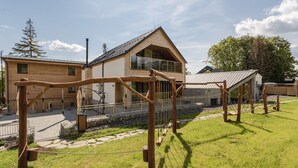 A modern house with a large glass window, a wooden deck, and a stone pathway.