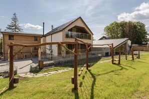 A modern house with a large glass window, a wooden deck, and a stone pathway.