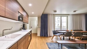A modern kitchen with wooden cabinets, a built-in oven, and a large window with curtains. - Elegant Haussmannian Retreat in the Heart of Paris (Paris)