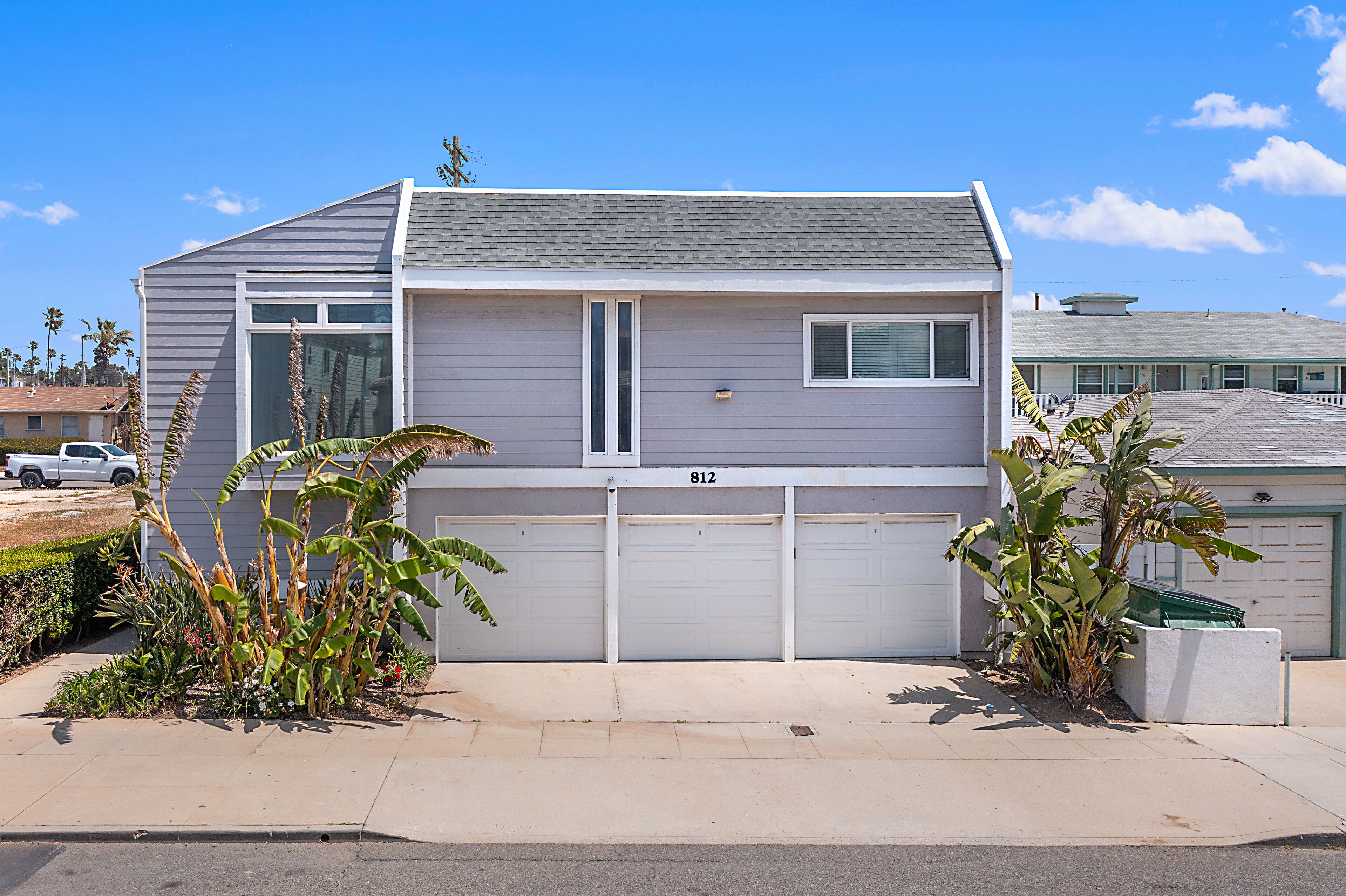 A two-story house with a garage, number 812, and a small front yard with plants.