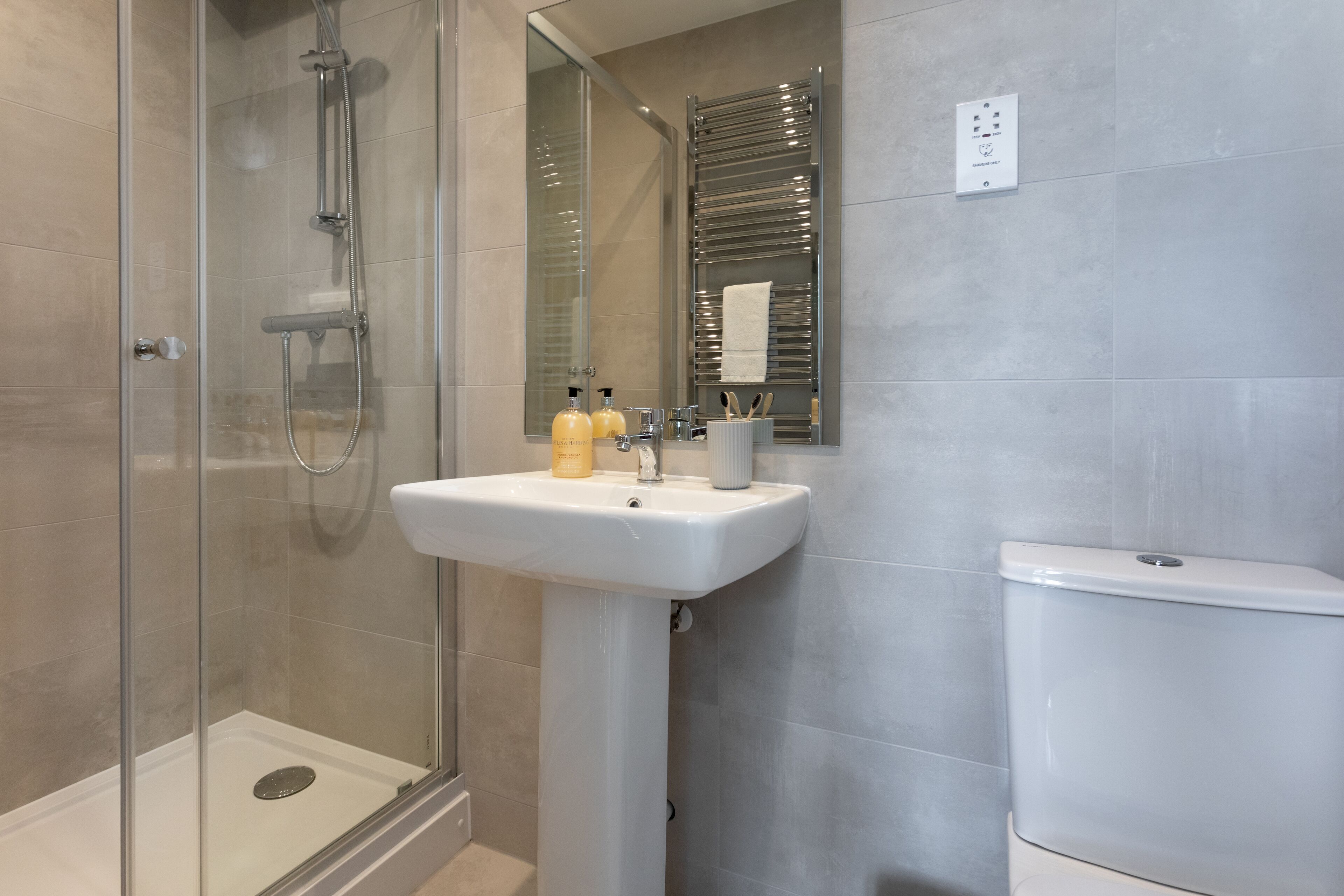 A modern bathroom with a glass shower enclosure, a pedestal sink, and a toilet.