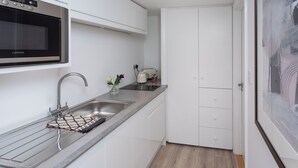 A modern kitchen with white cabinets, a stainless steel sink, a microwave, and a kettle. - No.192 Oxford (Oxford)