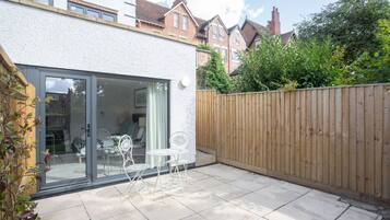 A patio with a glass door leading to a room, a wooden fence, and a view of neighboring houses.