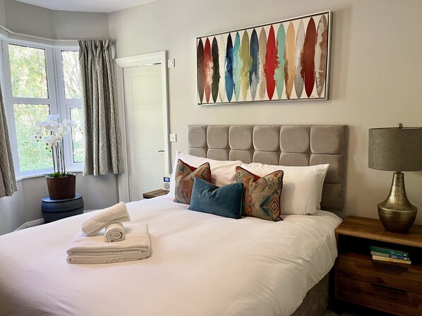A neatly made bed with white linens, a potted orchid, and a stack of folded towels. - No.192 Oxford (Oxford)