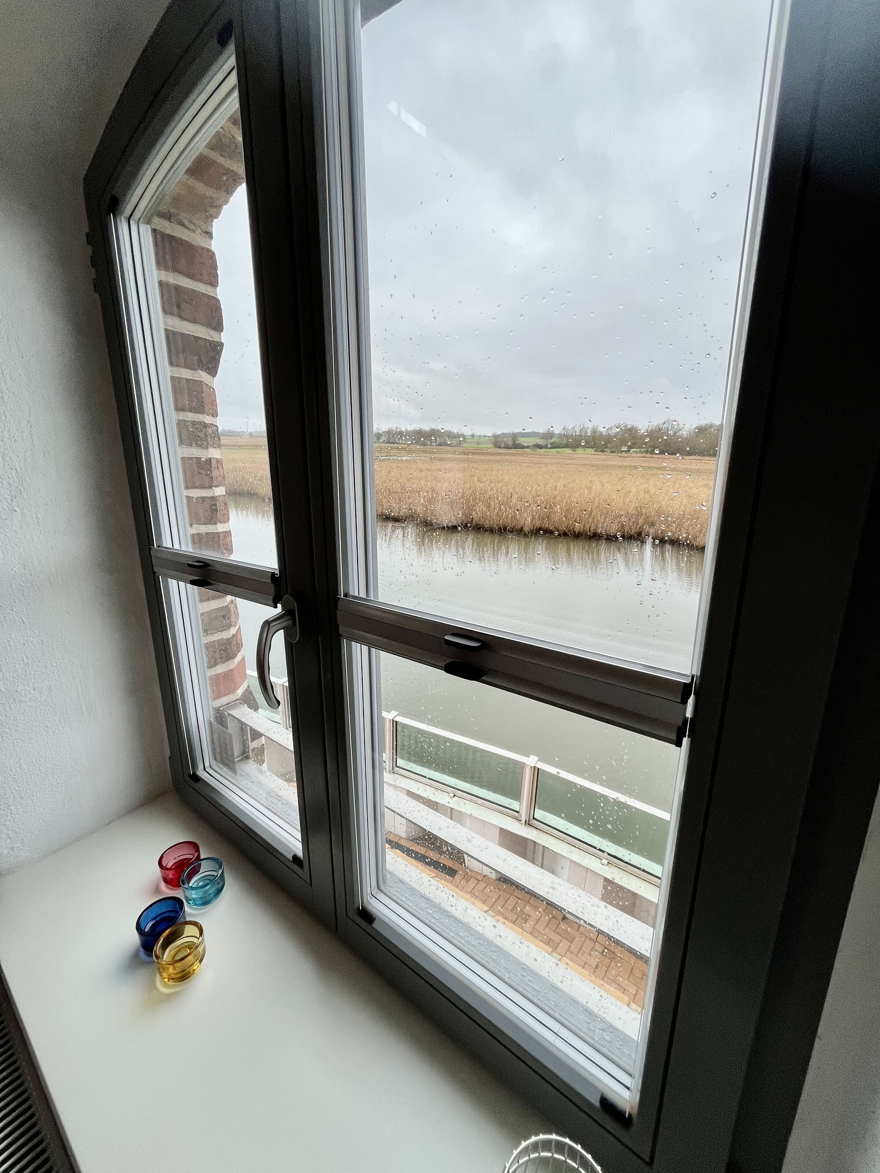 A window with a view of a brick wall and a field.