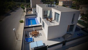 A modern two-story building with a rooftop pool, outdoor seating, and a view of the surrounding landscape. - PICAFORT2, PRIVATE POOL, free wifi, beach, air conditioning, barbecue (IB)