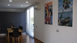 A modern dining area with a wooden table and chairs, a kitchen in the background, and two paintings on the wall. - PICAFORT2, PRIVATE POOL, free wifi, beach, air conditioning, barbecue (IB)