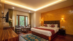 Un dormitorio con cabecera de madera, cama grande con ropa blanca, mesita de noche, escritorio con silla y ventana con cortinas.