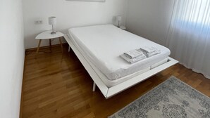 Een moderne slaapkamer met een enkel bed, een nachtkastje, een lamp, een vloerkleed en een ingelijst beeld aan de muur.