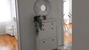 Een moderne, minimalistische kamer met een witte dressoir, een ronde spiegel en een potplant.