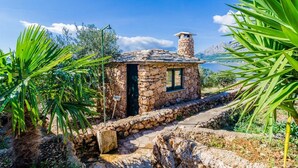 A stone house with a chimney, surrounded by greenery and a clear sky. - Villa Sea Edge (Orebic)