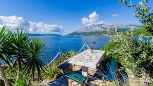 A stone table with a bench, overlooking a lake with mountains in the background. - Villa Sea Edge (Orebic)