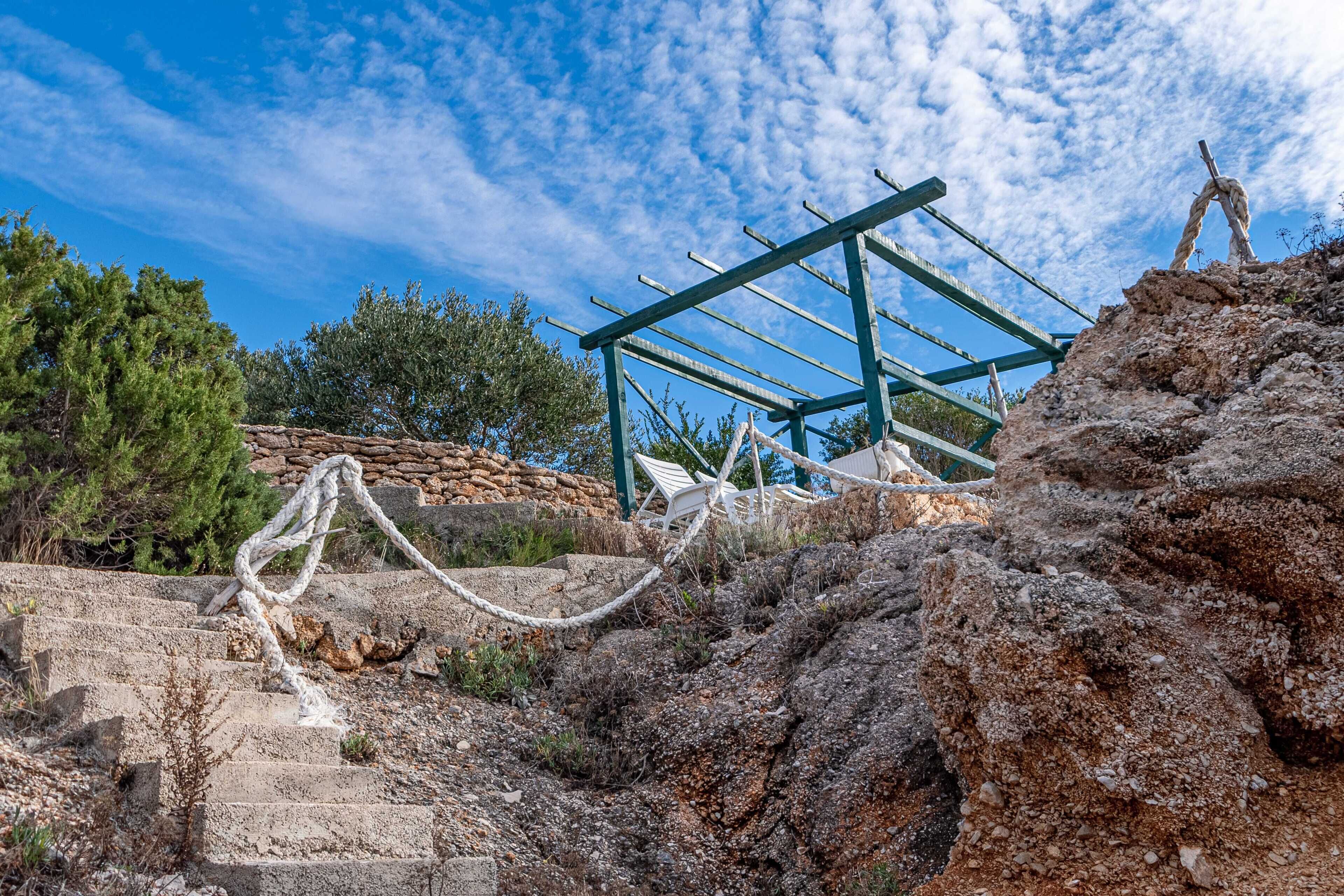 Un terreno rocoso al aire libre con una estructura metálica, posiblemente una plataforma de observación, rodeado de árboles y vegetación.