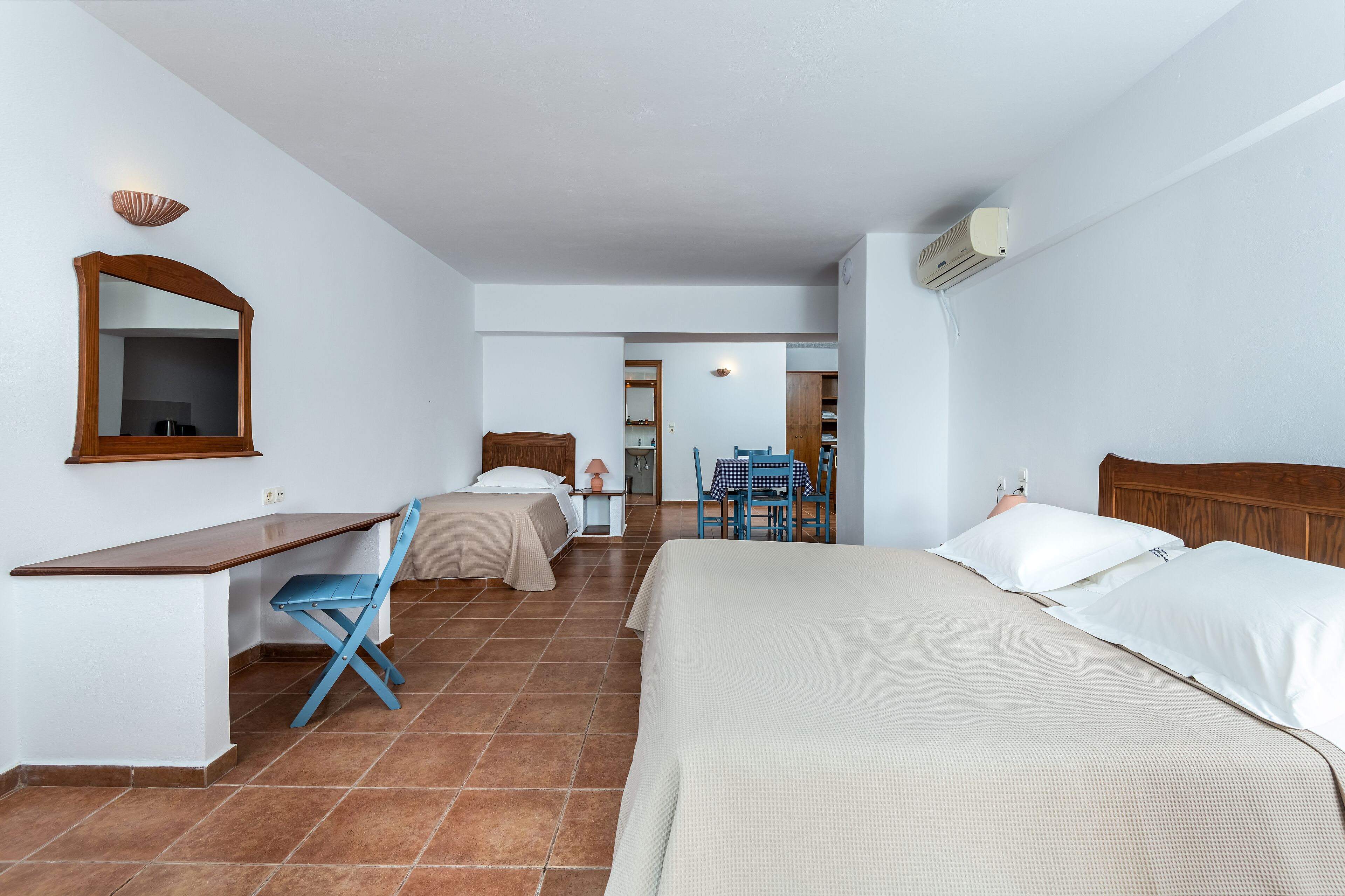 A hotel room with a bed, desk, chair, and a small table with chairs.