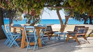 A table and chairs set under a tree by a beach. - Olympia Mare (Kos)
