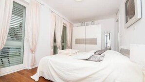 A bedroom with a bed, a wardrobe, and a window with blinds. - Apartment Vesna (Dubrovnik)