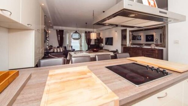 A modern kitchen with a central island, built-in oven, and a dining area with a table and chairs. - Apartment Vesna (Dubrovnik)