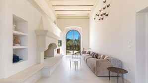 A modern living room with a beige sofa, a small round table, and a large arched window. - 2874 Masseria Marchese by Perle di Puglia (Montesano Salentino)