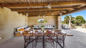 An outdoor dining area with a wooden table, metal chairs, and a thatched roof. - 2874 Masseria Marchese by Perle di Puglia (Montesano Salentino)