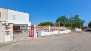 A modern building with a white facade, a red gate, and a paved entrance area with outdoor seating. - 3033 Villetta Angela by Barbarhouse (Melendugno)